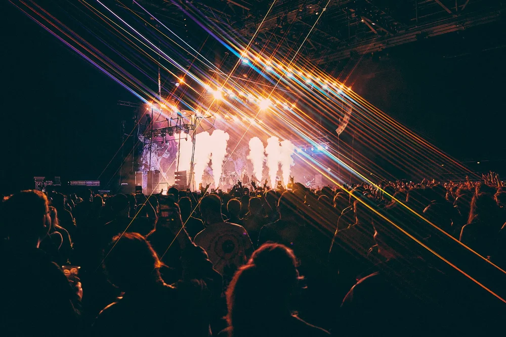 People gathered in front of a brightly lit concert stage
